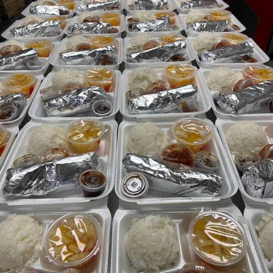 Rows of takeout trays filled with white rice, foil-wrapped entrées, soup containers, and small cups of sauces.