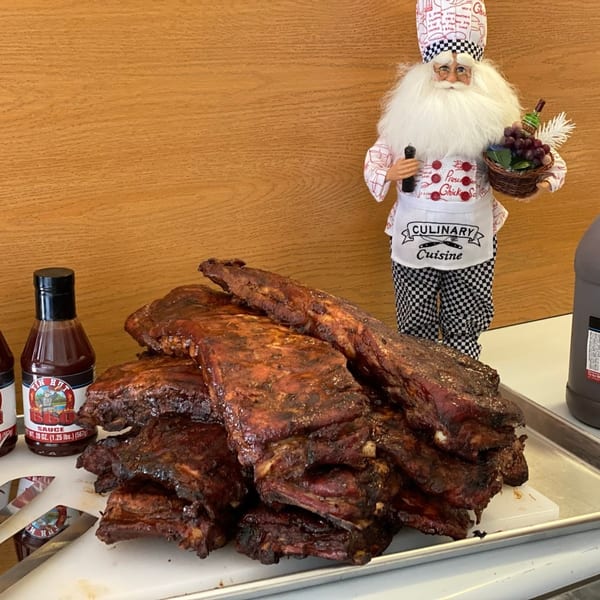 Tin Hut BBQ ribs on a tray with barbecue sauce bottles and a chef figurine.