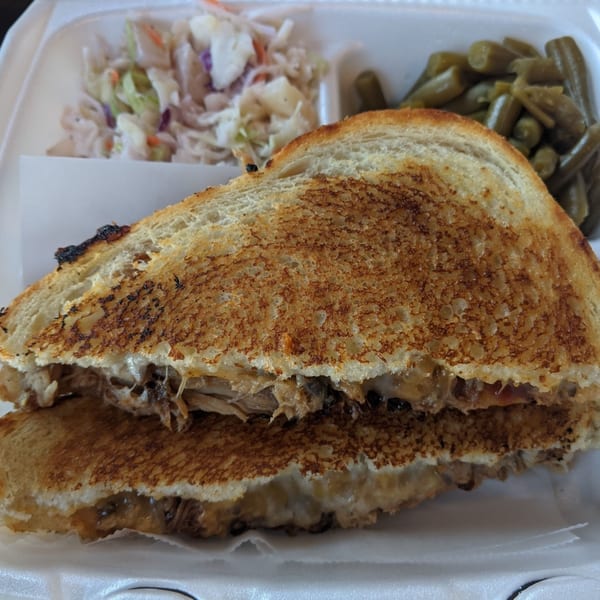 Tin Hut BBQ's grilled sandwich with pulled pork, melted cheese, coleslaw, and green beans.