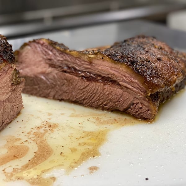 Close-up of sliced, juicy Tin Hut BBQ brisket with a dark, seasoned crust on a cutting board.