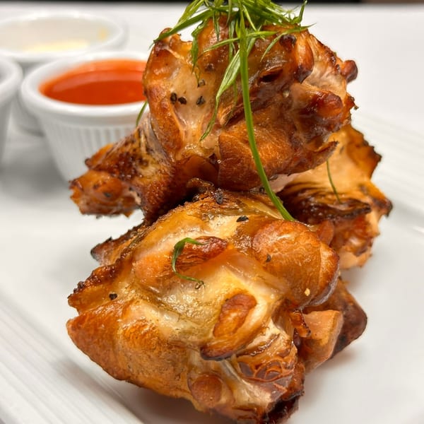 Tin Hut BBQ's crispy chicken wings, garnished with fresh herbs, served with dipping sauces.