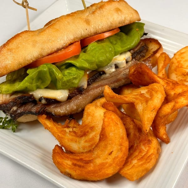 Tin Hut BBQ's brisket sandwich with melted cheese, lettuce, tomato, and curly fries on a white plate.
