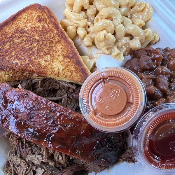 Tin Hut BBQ plate with brisket, pulled pork, mac and cheese, baked beans, and Texas toast.